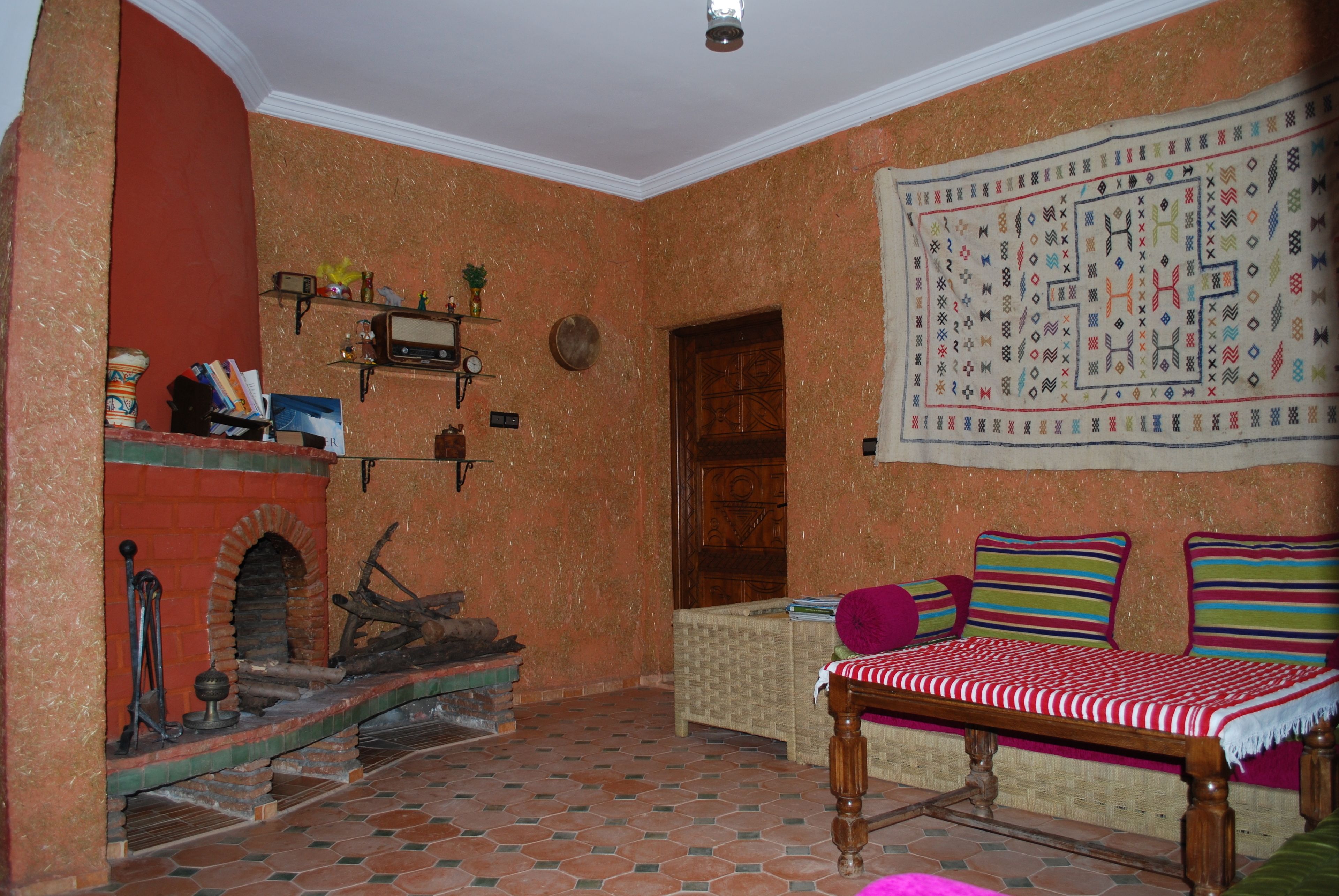 A cozy living room with a fireplace, a sofa, and a patterned tapestry.