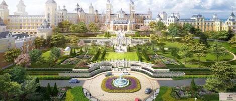 Un hotel elegante con una fuente central, jardines cuidados y arquitectura clásica.