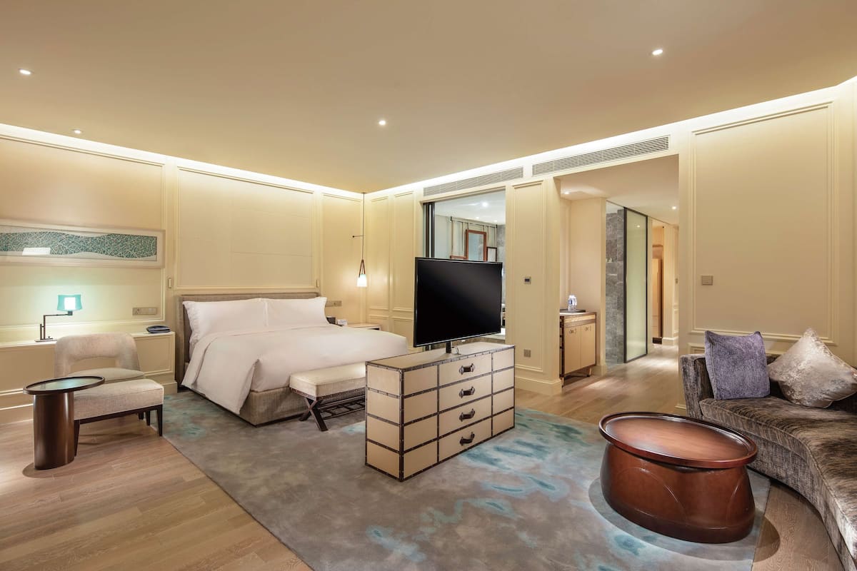 Een moderne hotelkamer met een bed, een televisie, een dressoir, een stoel en een bank.