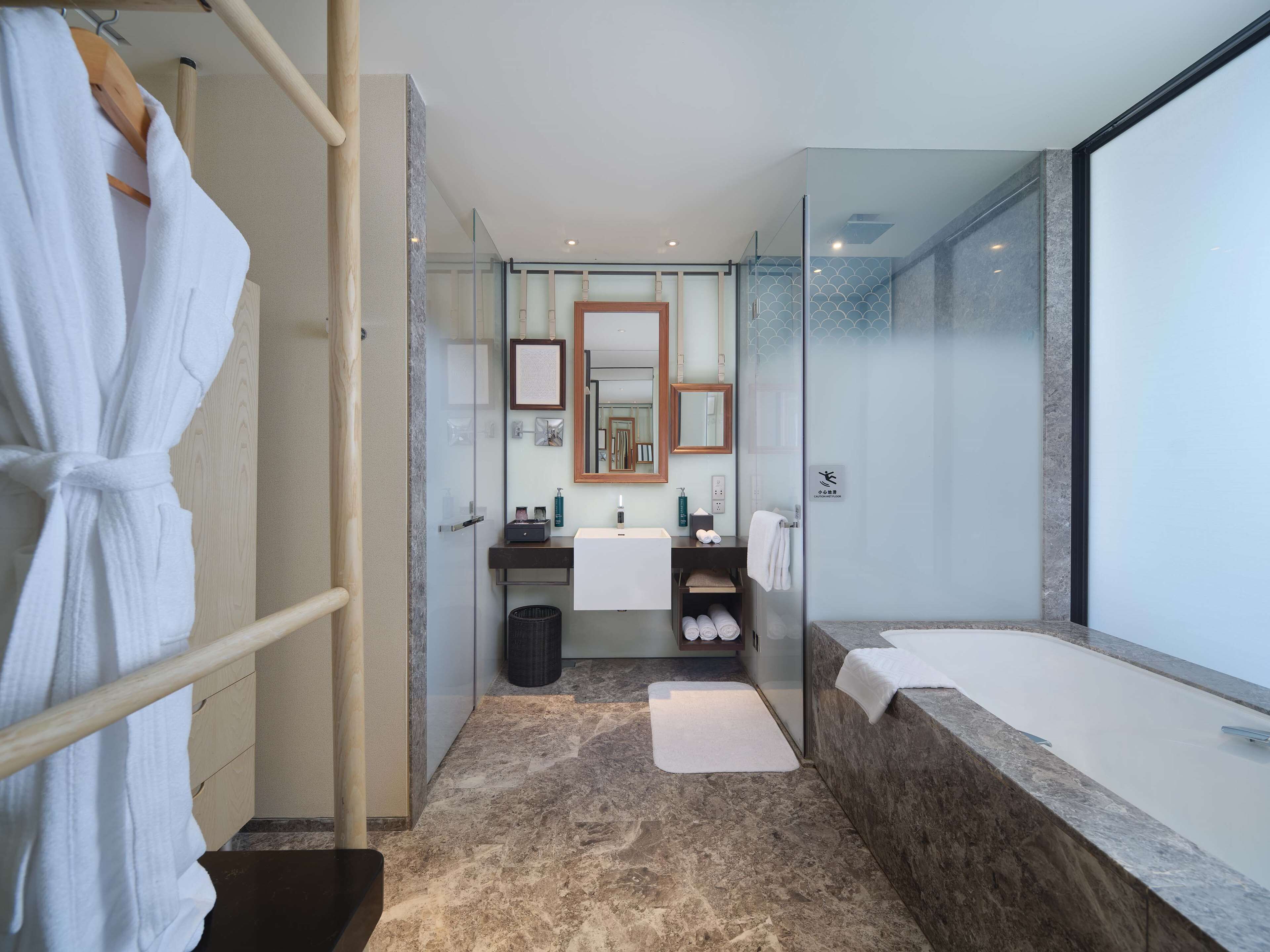 A modern bathroom with a glass shower enclosure, a large mirror, a bathtub, and a robe rack.