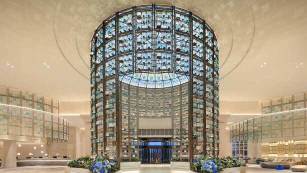 Un hall d’entrée spacieux doté d’une verrière centrale, de coins salon et d’un comptoir d’accueil.