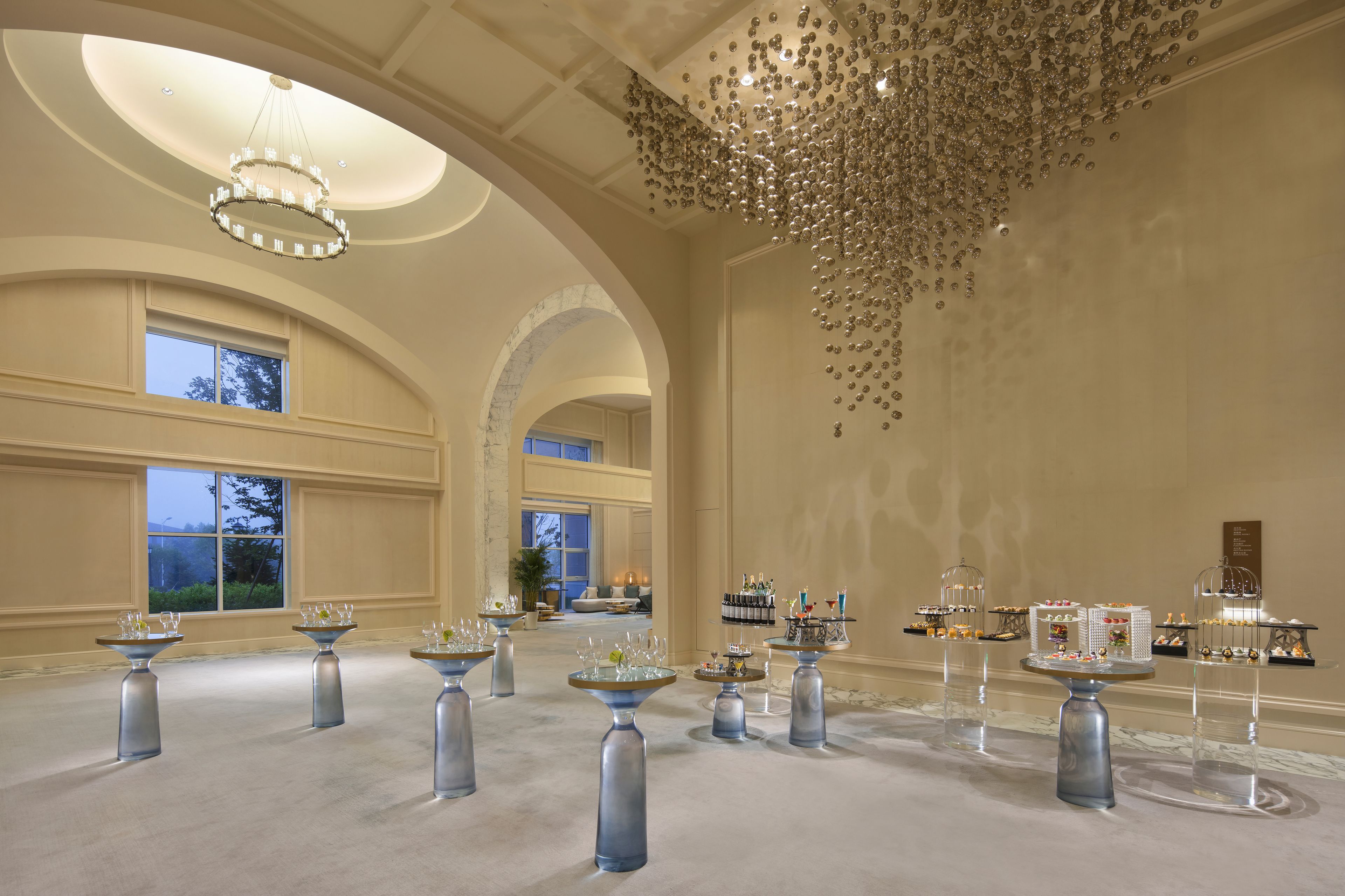 A spacious hall with multiple tables, each with a glass centerpiece and a decorative item on top.