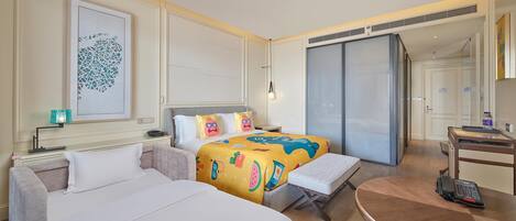 Una habitación de hotel con cama, sofá, escritorio y teléfono, y un ventanal grande.