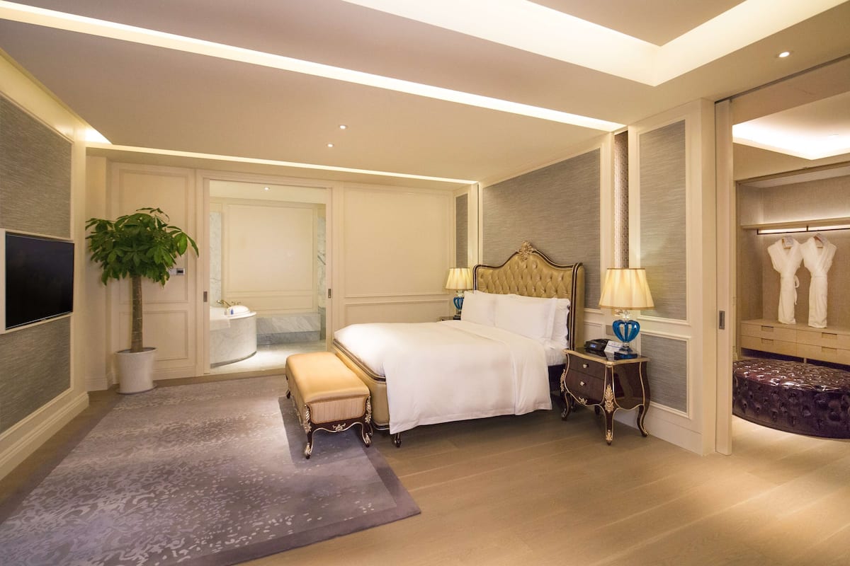 Een ruime hotelkamer met een groot bed, een zithoek, een kaptafel en een televisie.