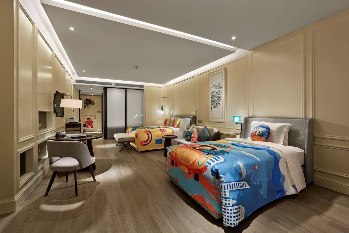 A hotel room with a large bed, a desk, a chair, and a sofa.