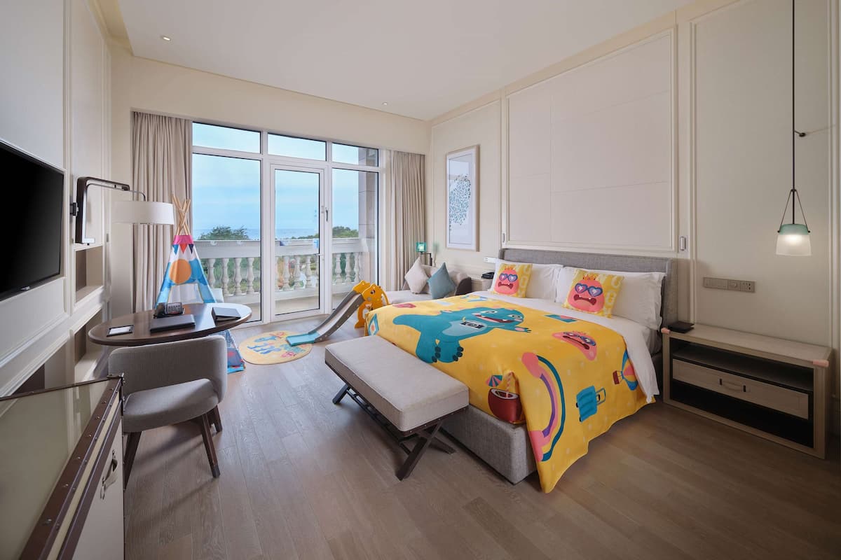 Hotelkamer met een groot bed, een bureau met stoel, een televisie en een balkon met uitzicht.