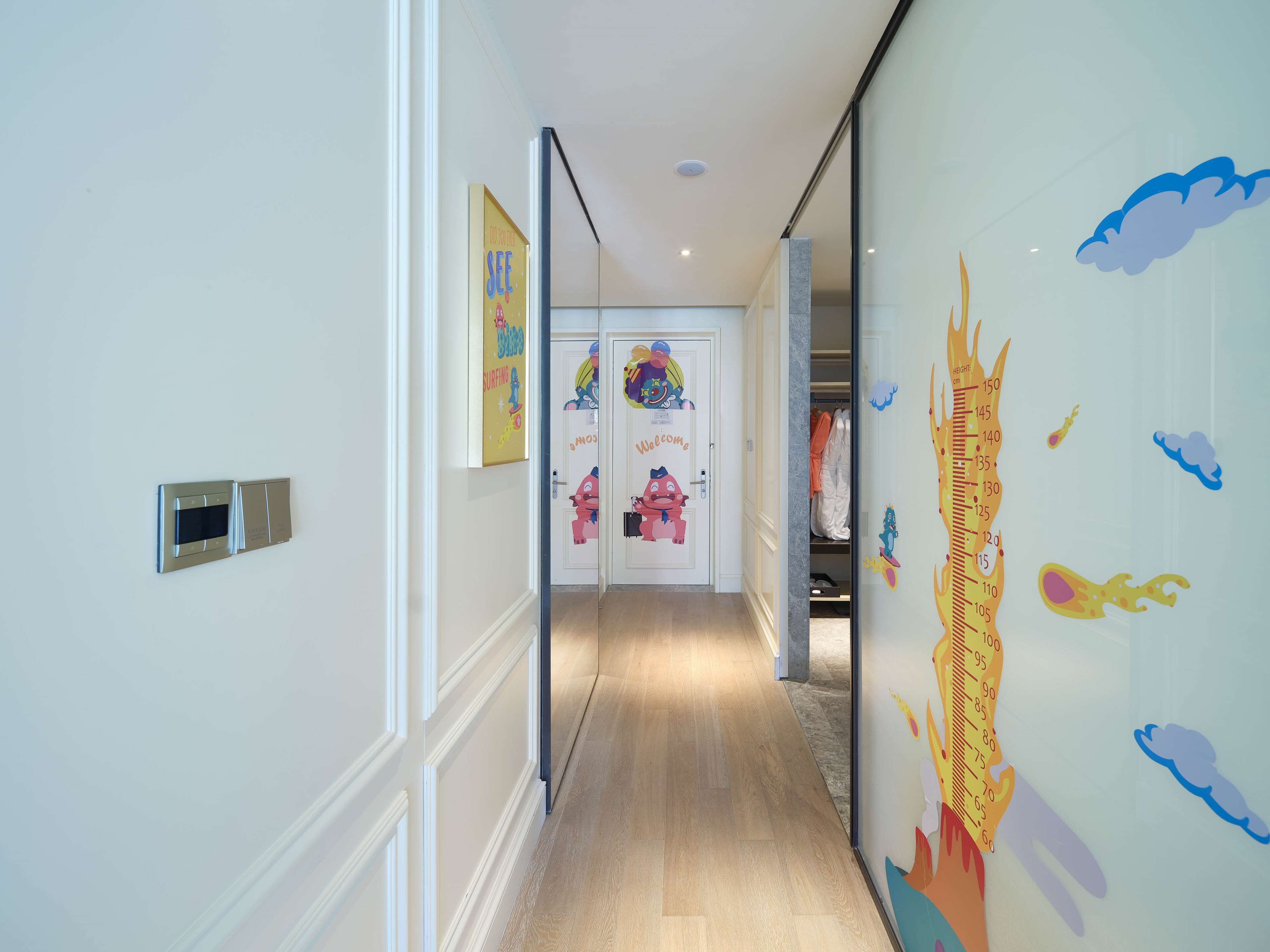 A hallway with a height chart on the wall, a welcome sign, and a children's room with cartoon characters.