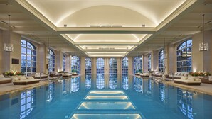Une grande piscine intérieure dotée de nombreux espaces de détente et de grandes fenêtres.