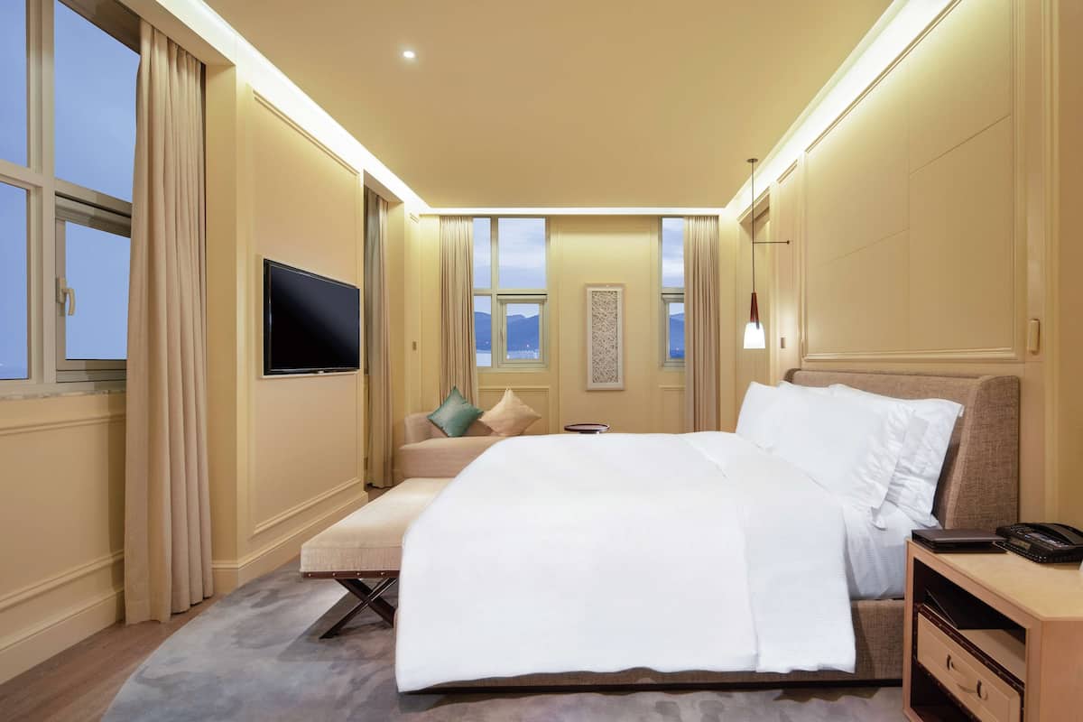 Een hotelkamer met een groot bed, een televisie, een nachtkastje en uitzicht op de bergen.