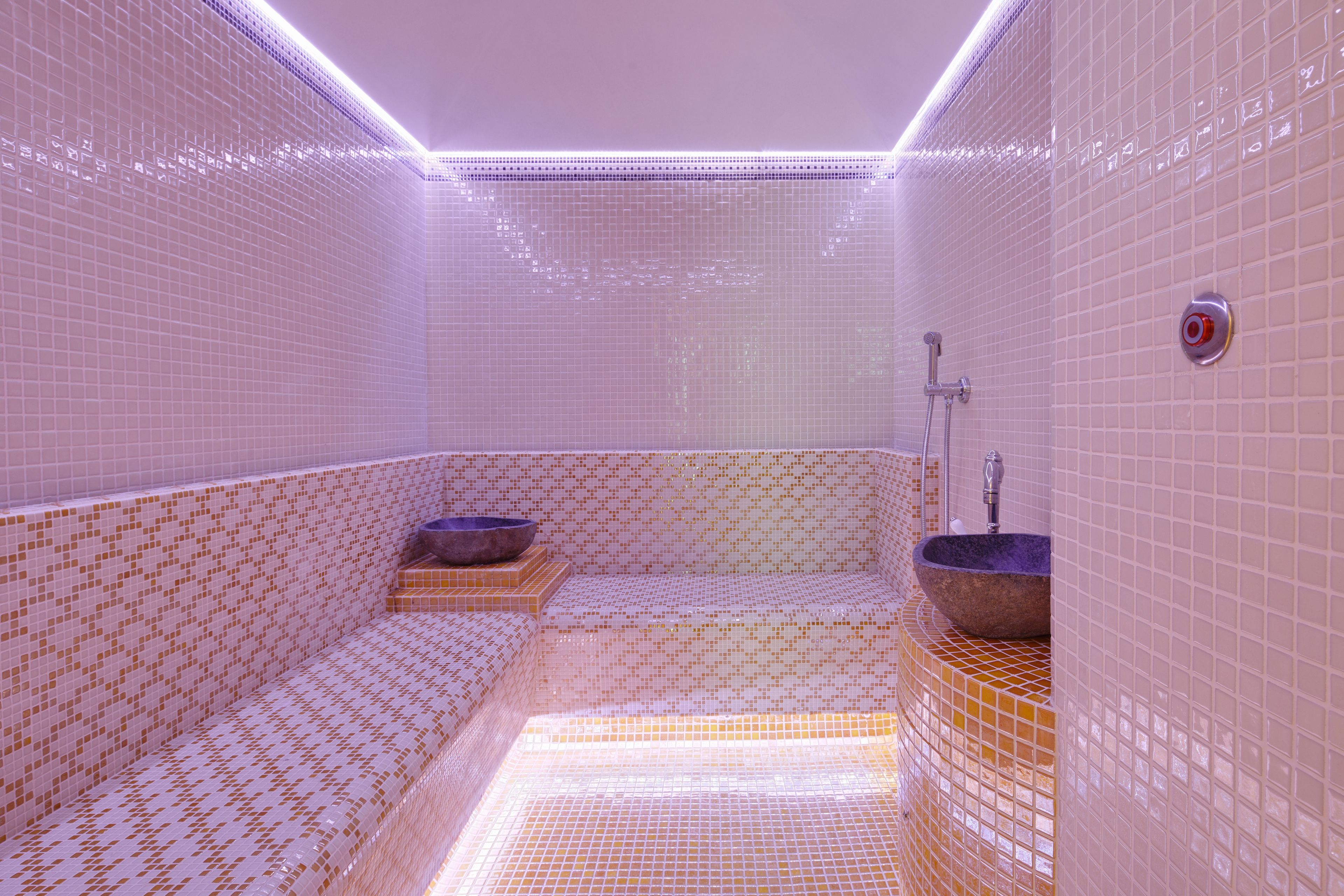 A bathroom with a tiled floor, a sink, and a shower area.