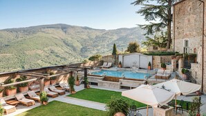 Ein Poolbereich mit Liegestühlen, einem Whirlpool und Blick auf Berge.