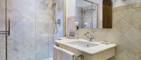 A modern bathroom with a glass-enclosed shower, a sink with a mirror, and a towel rack.