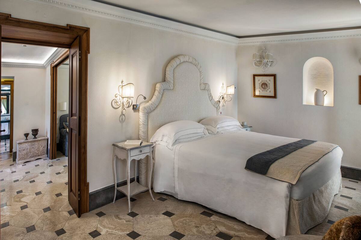 Een slaapkamer met een groot bed, een nachtkastje, een spiegel en een kroonluchter.