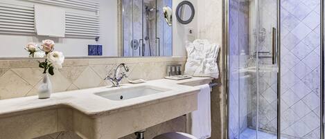 A bathroom with a double sink, a glass shower enclosure, and a vanity with a towel rack.