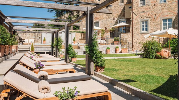 Eine Terrasse mit Liegestühlen, Steinmauern und Kübelpflanzen.