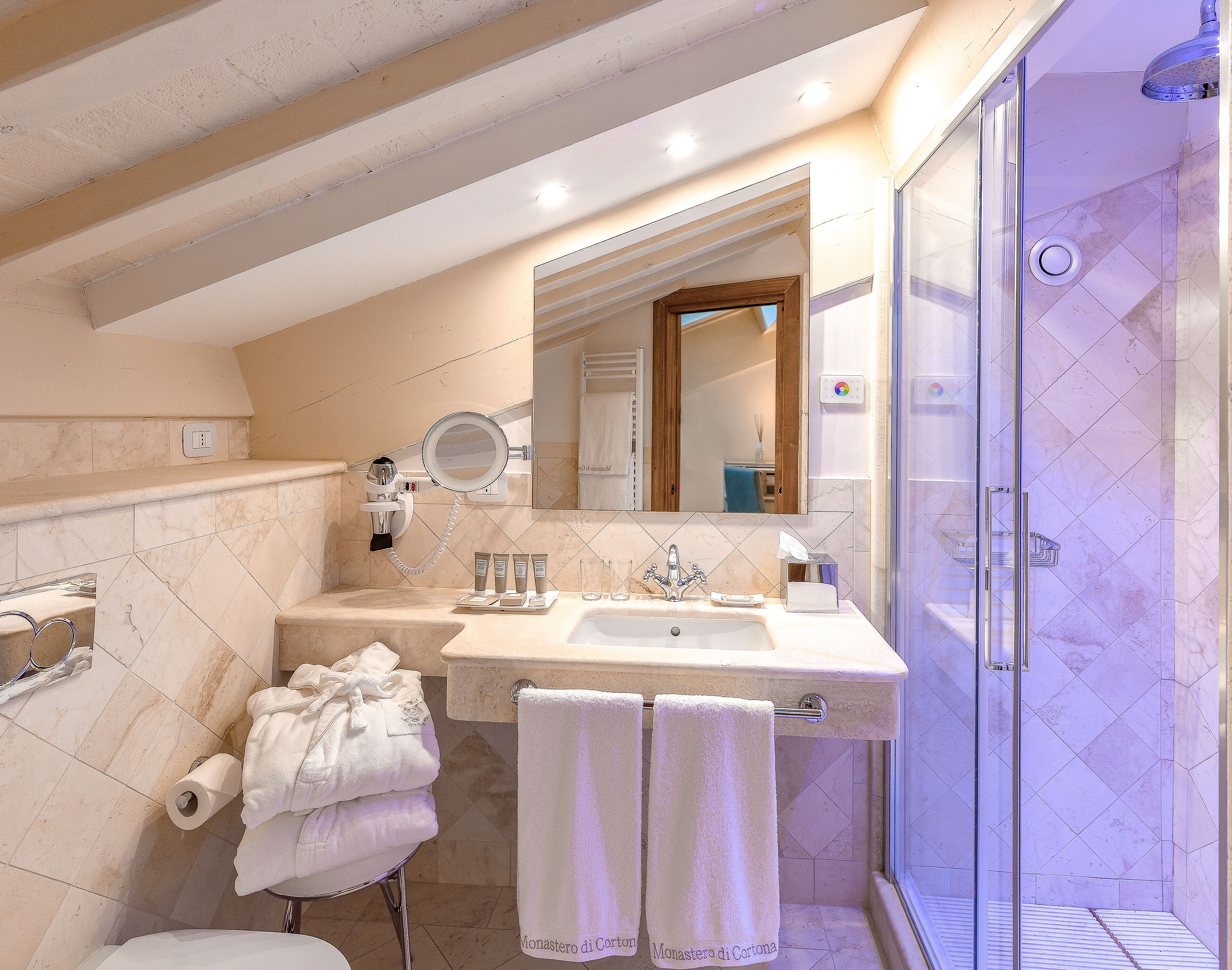 Un bagno con doccia, lavandino e articoli da toilette, e asciugamani.