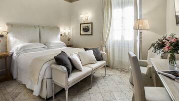 A hotel room with a bed, a sofa, a dining table, and a chair.