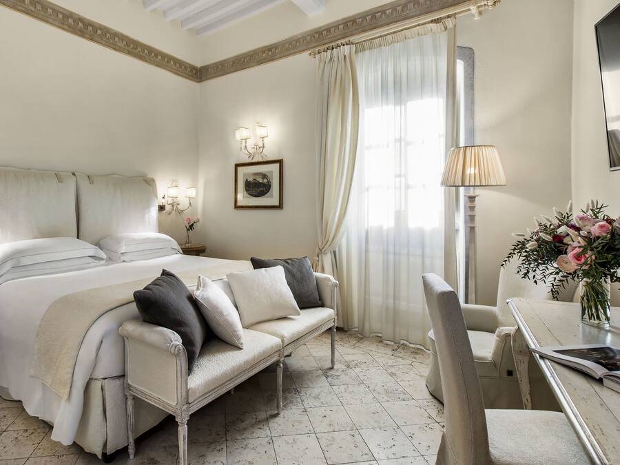 A hotel room with a bed, a sofa, a dining table, and a chair.