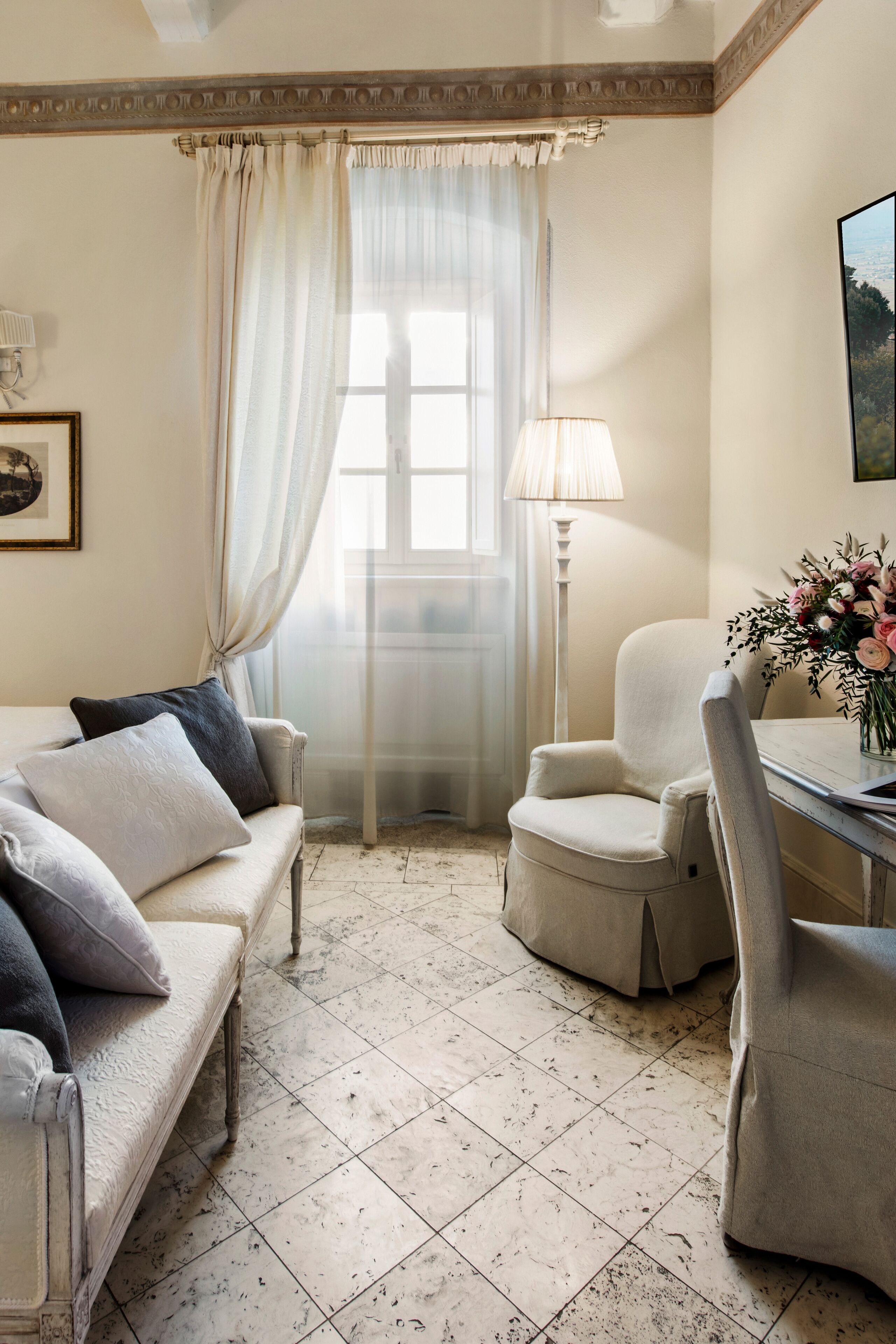 Een kamer met een bank, fauteuil en een tafel met een bloevas.