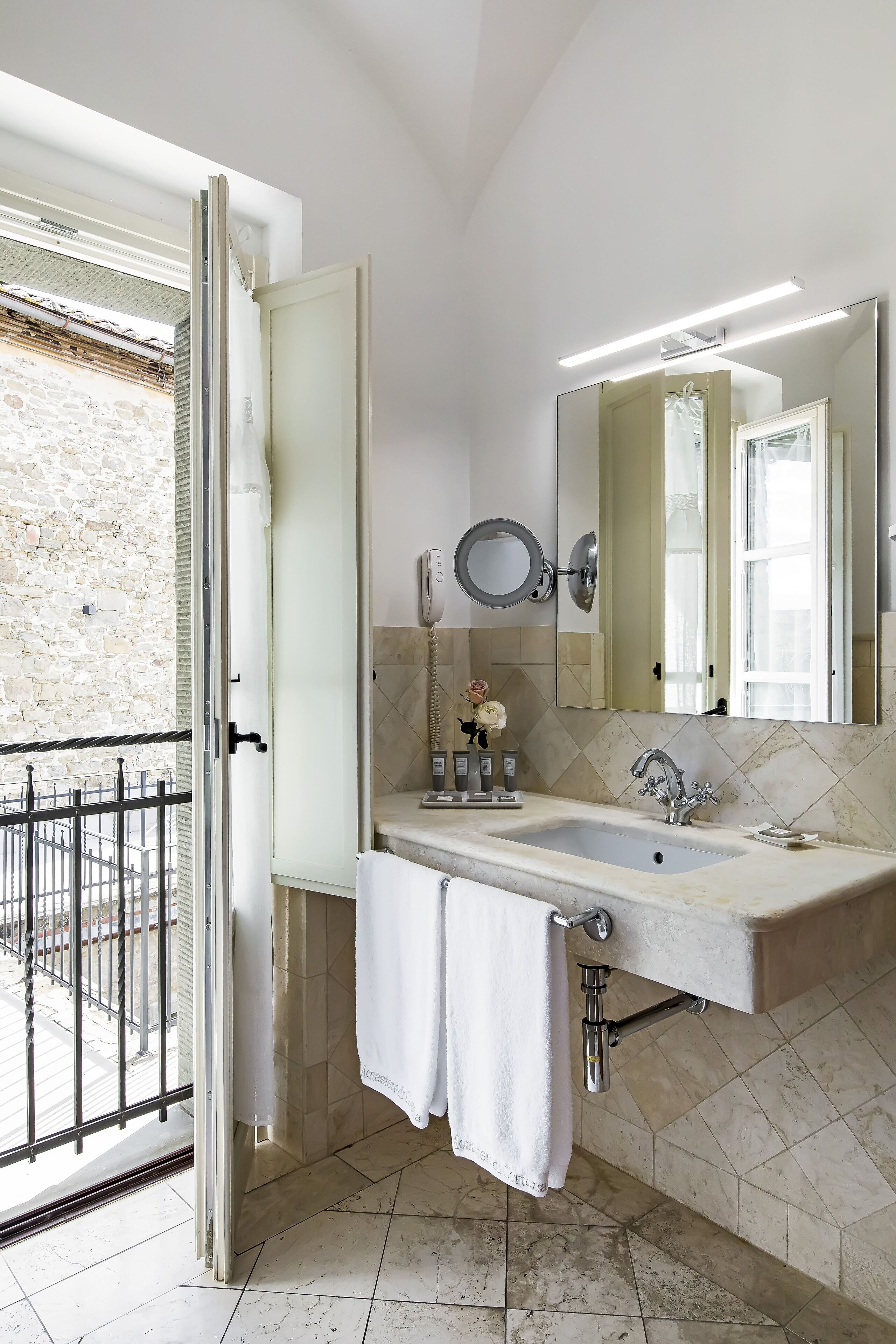 Un baño con un espejo grande, un lavabo y una toalla colgada en la puerta.