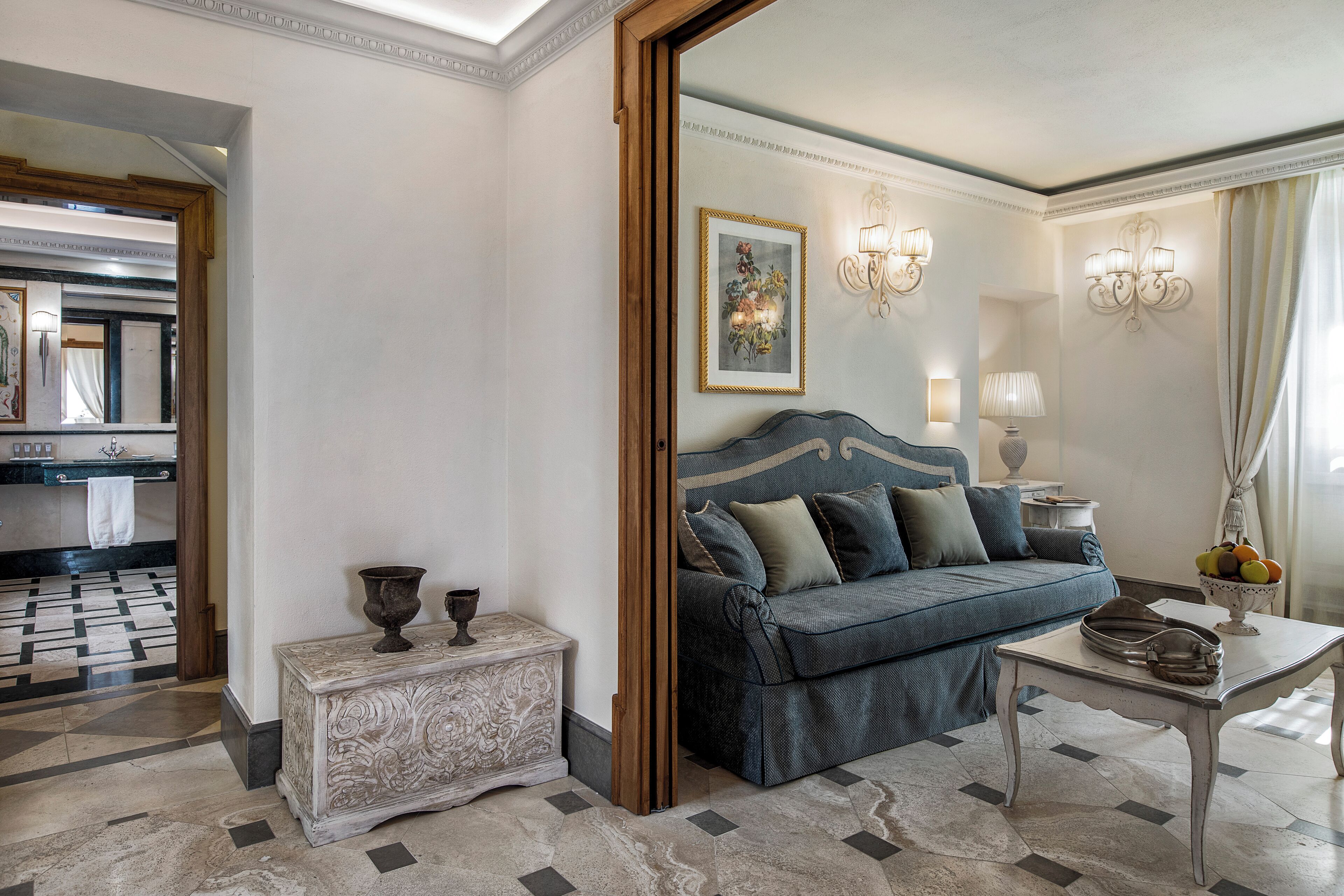 A room with a blue sofa, a small table with a vase, and a mirror in the background.