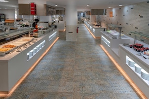 En moderne buffetopstilling med flere madstationer, et centralt anretningsområde og en ren flisebelagt gulv.