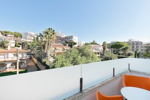 A balcony with orange chairs and a table, overlooking a residential area with various buildings and greenery. - Hotel Best Lloret Splash (Lloret de Mar)