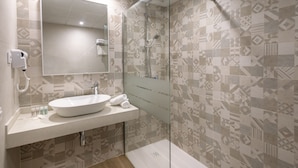 A modern bathroom with a large mirror, a sink, and a shower area. - Hotel Best Lloret Splash (Lloret de Mar)