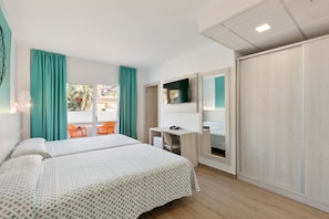 A hotel room with two beds, a desk, a chair, and a TV.