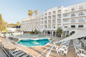 Un hotel con piscina, zona de estar al aire libre y varios balcones.