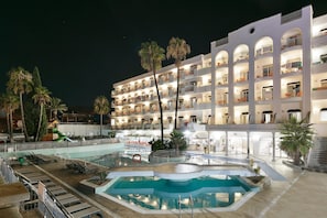 Un hotel con varios balcones, piscina y palmeras.