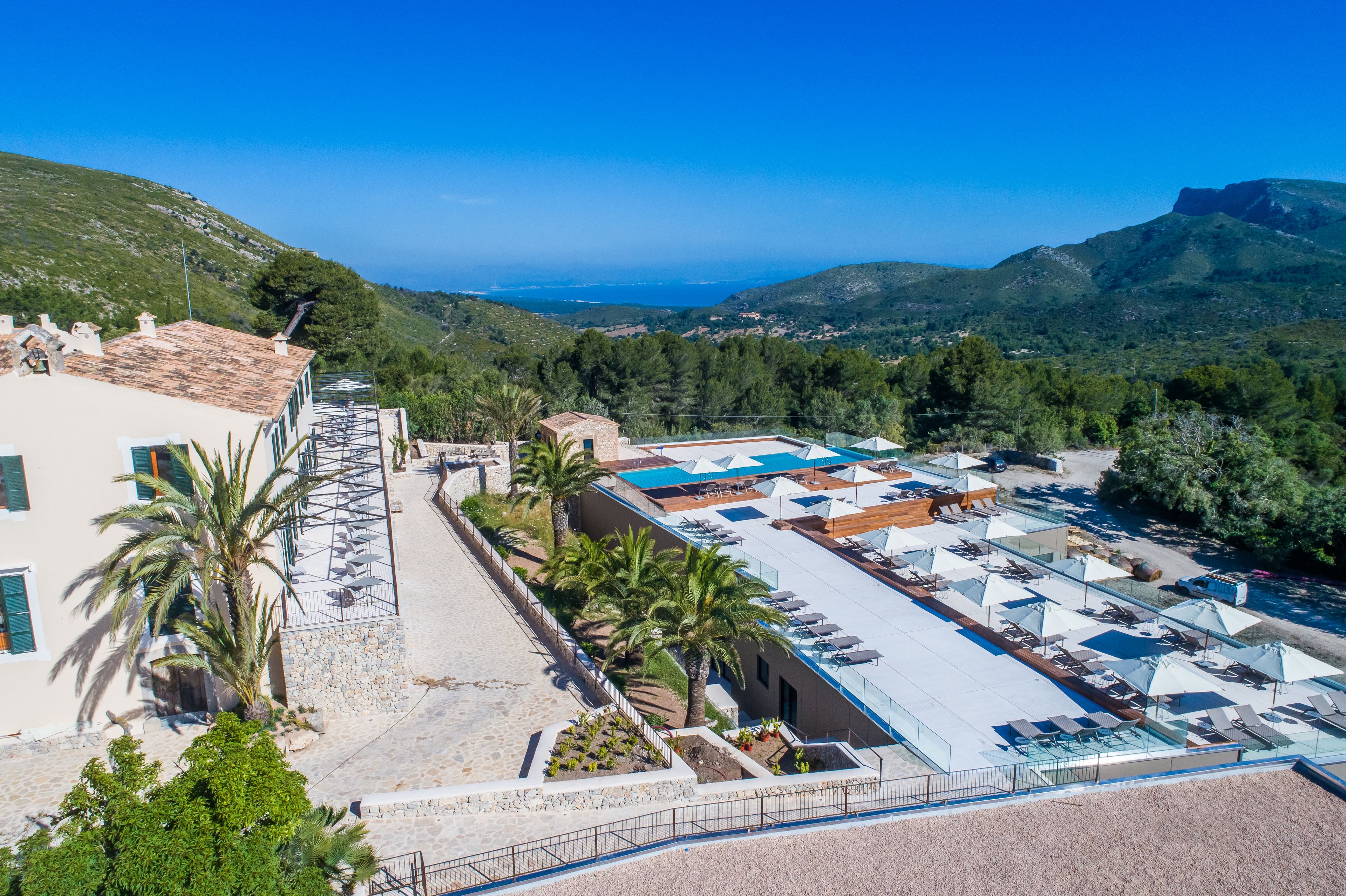 Zona de piscina en la azotea con tumbonas y sombrillas, rodeada de vegetación y con vistas a un paisaje costero.