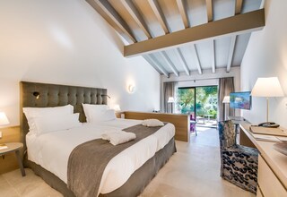 A modern hotel room with a large bed, a desk, and a view of the outdoors.