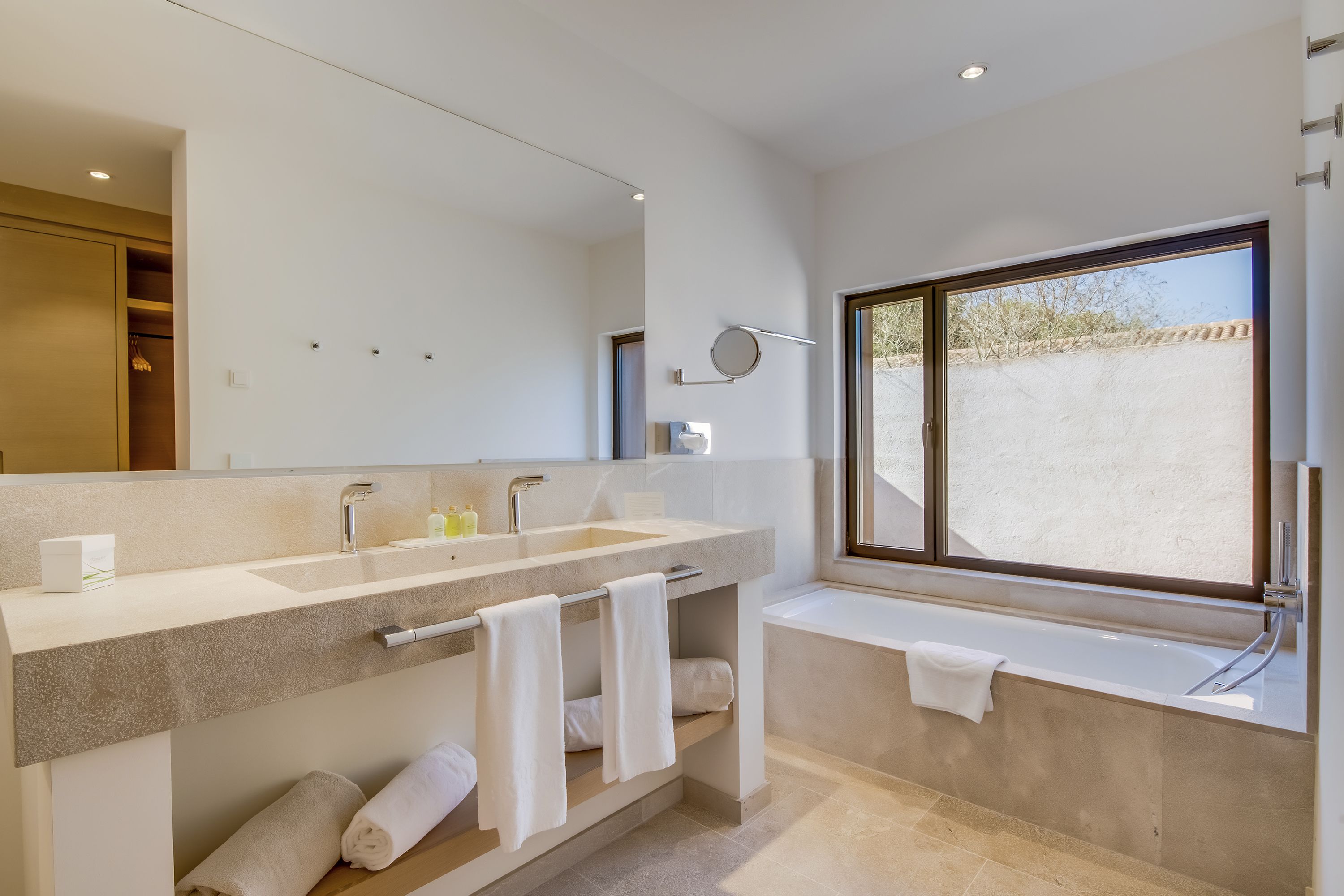 Ein modernes Badezimmer mit großem Spiegel, zwei Waschbecken und einer Badewanne.