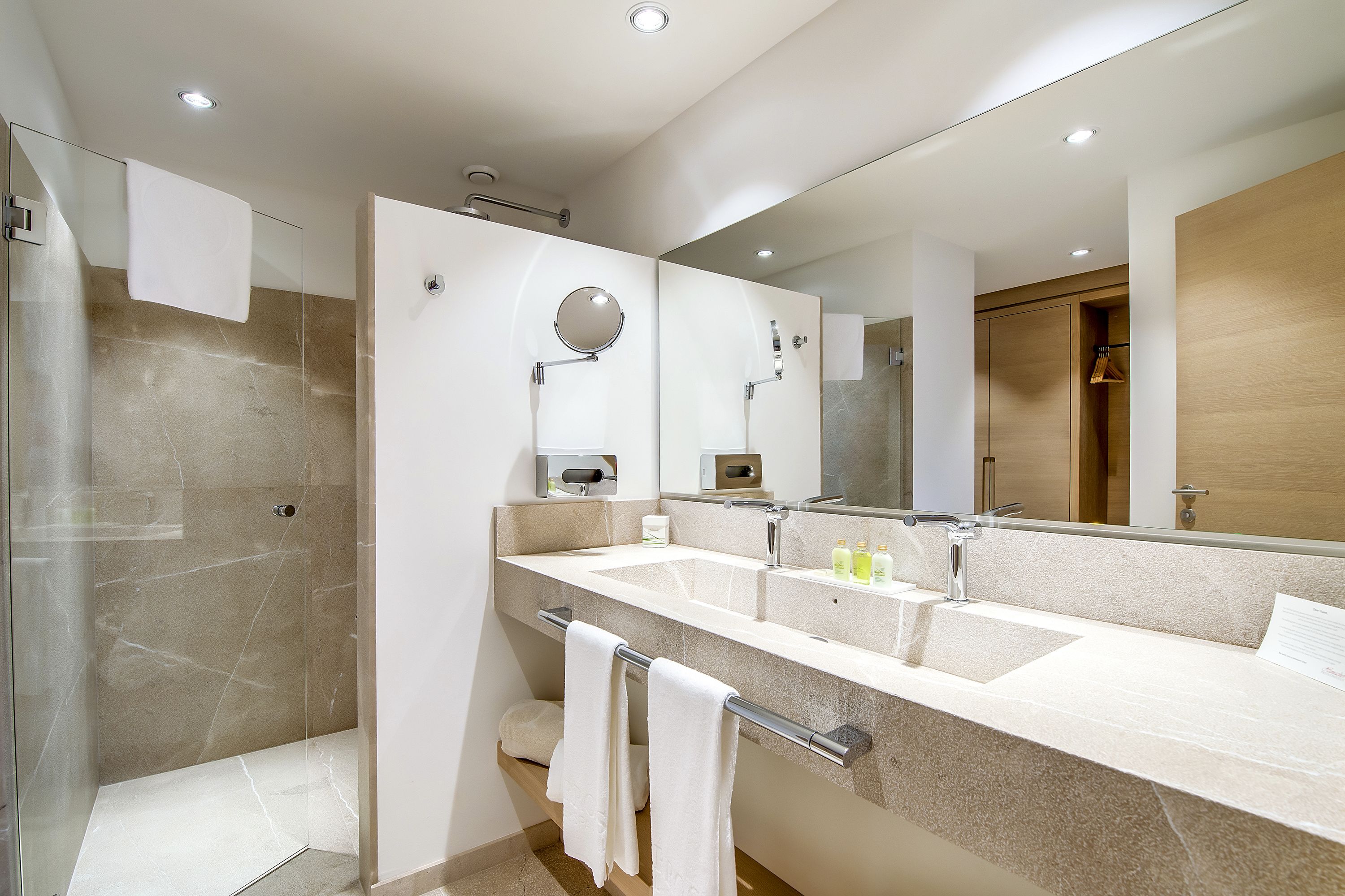 A modern bathroom with a glass shower enclosure, a large mirror, and a dual sink vanity.