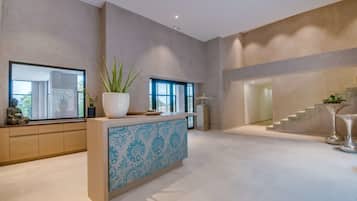 Un área de recepción moderna con un ventanal grande, un mostrador de recepción y una escalera que conduce a un piso superior.