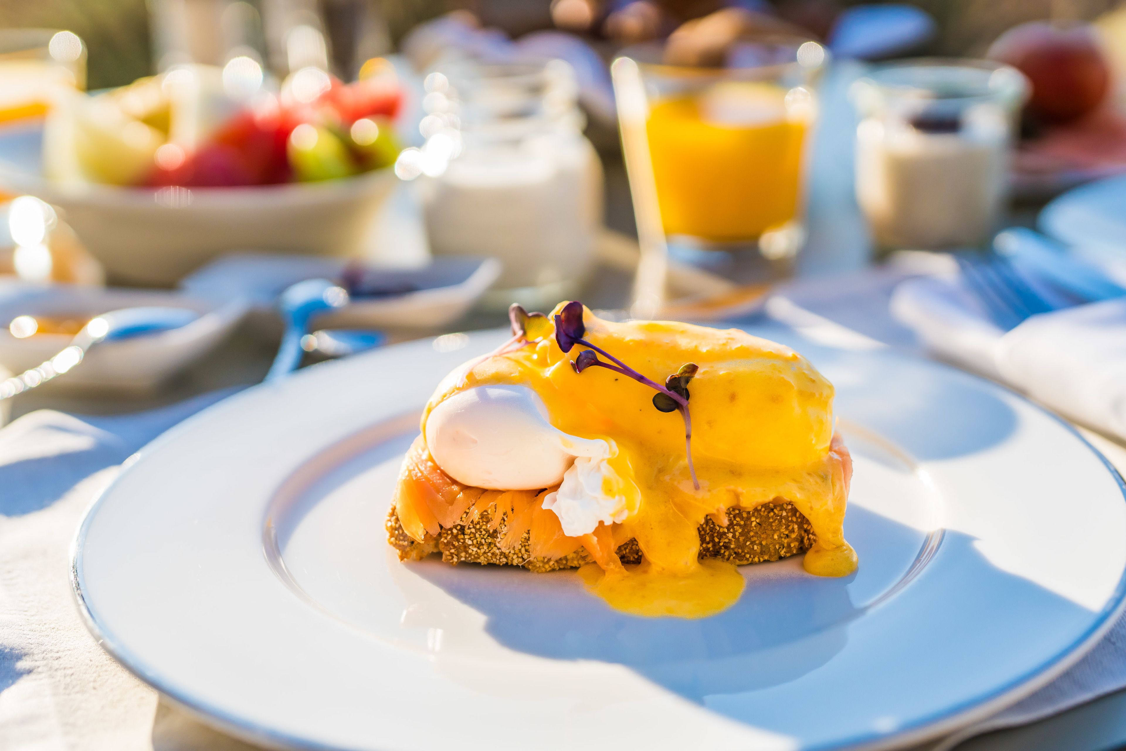 Ein Frühstücksteller auf weißem Geschirr, im Hintergrund ein Glas Orangensaft.