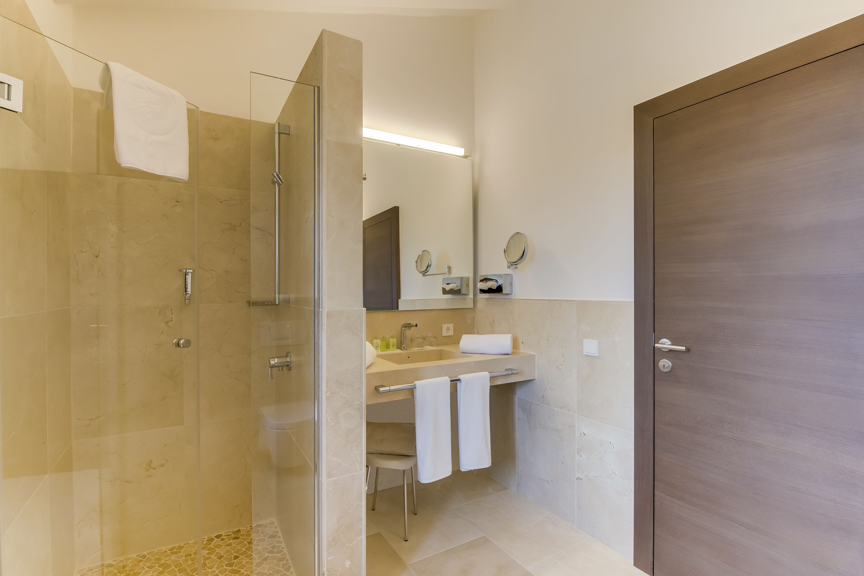 Une salle de bain moderne avec une douche à parois de verre, un lavabo avec un miroir et une porte.
