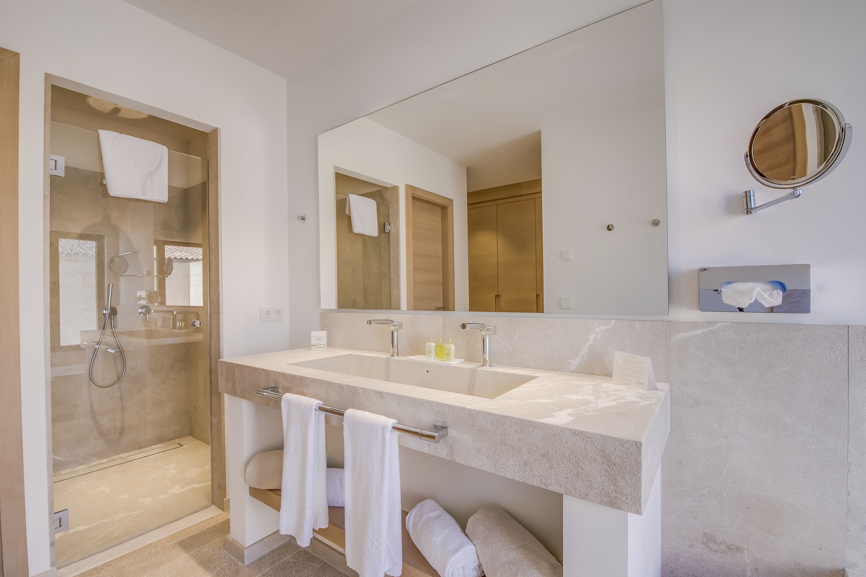 Une salle de bain moderne avec un grand miroir, deux lavabos et une douche à l’italienne.