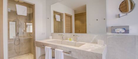 Une salle de bain moderne avec un grand miroir, deux lavabos et une douche à l’italienne.