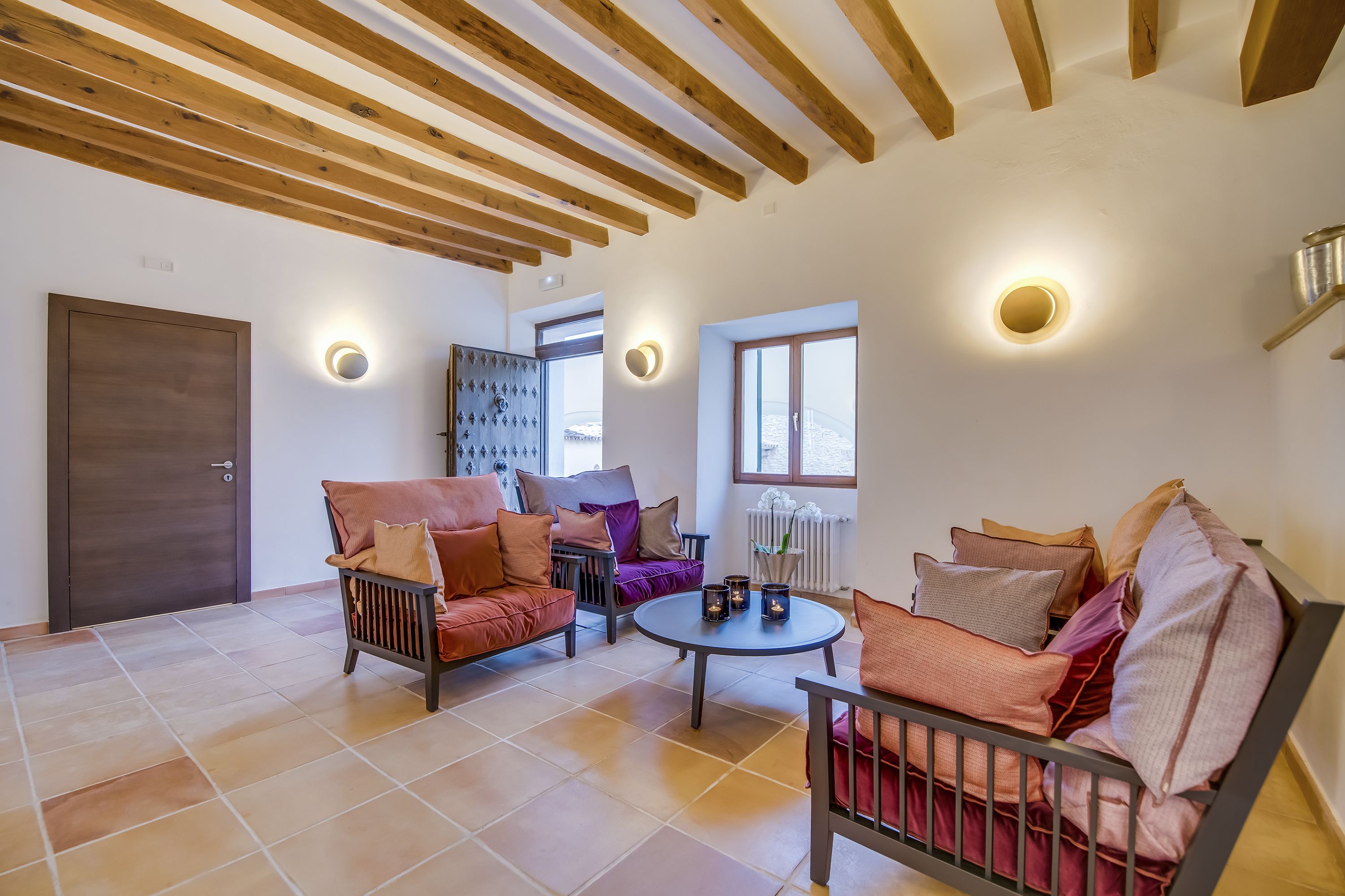 A spacious living area with wooden beams, two sofas with cushions, a coffee table, and a radiator.