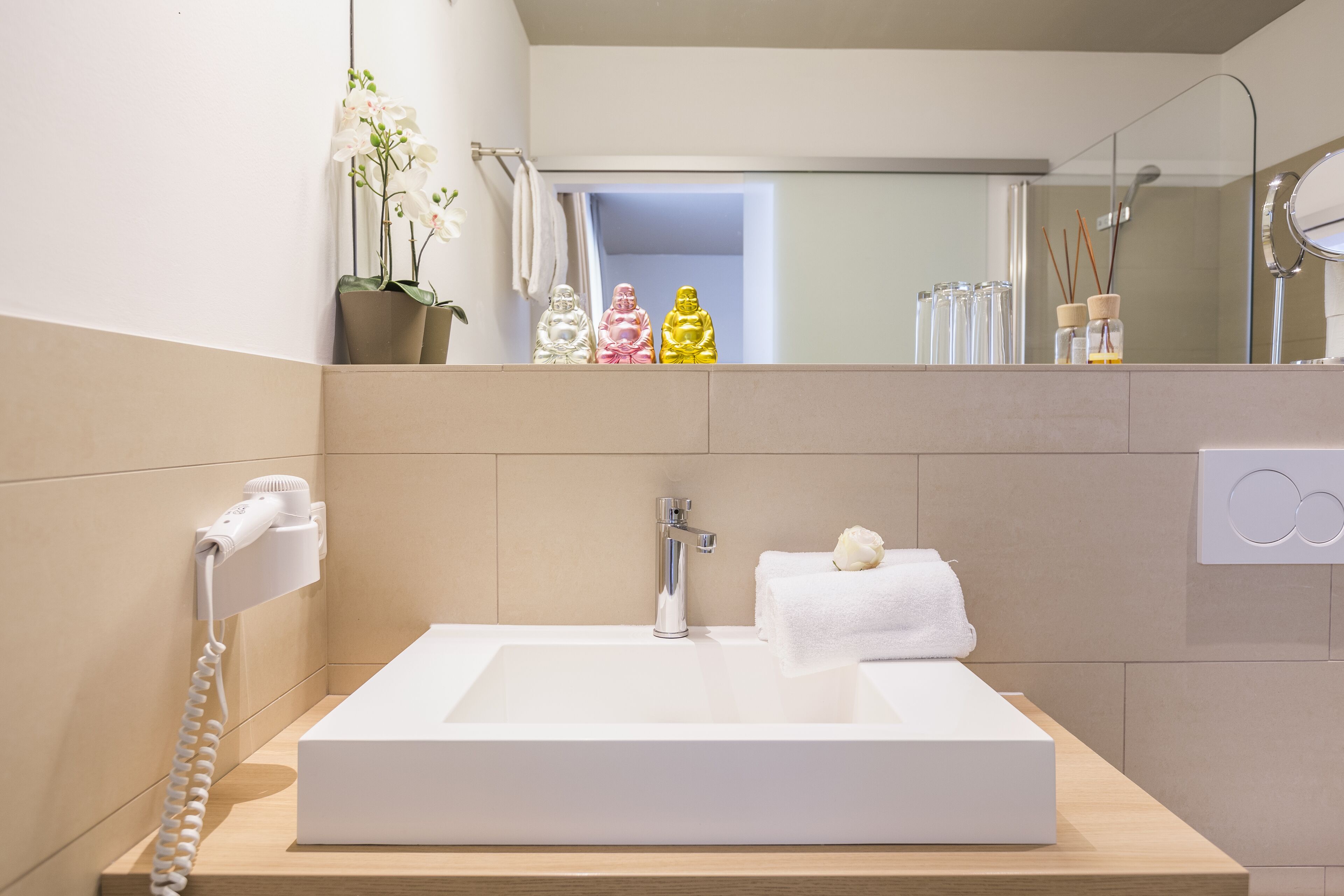 Une salle de bain moderne avec un grand lavabo blanc, un sèche-cheveux et un miroir.