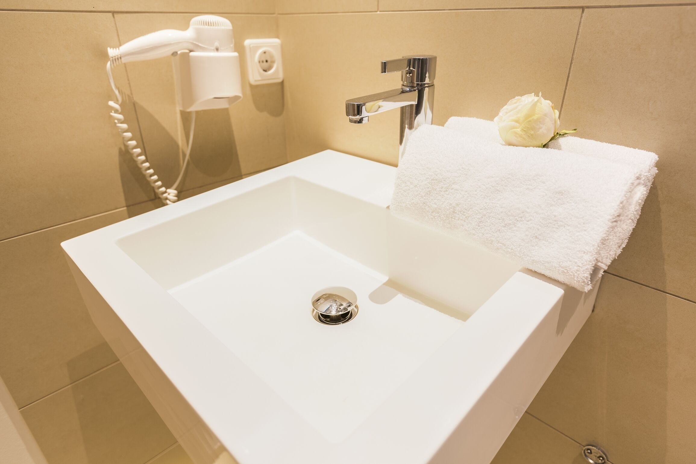 Une salle de bain avec un lavabo blanc, un sèche-cheveux et une serviette.