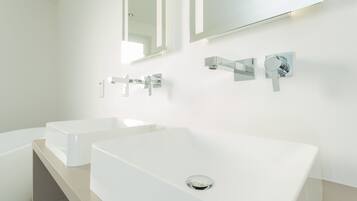A modern bathroom with two white sinks, chrome faucets, and a large mirror above.
