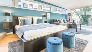 A modern bedroom with a large bed, a sofa, and a small table. - Room 4 & 5 Apartments (Salzburg)