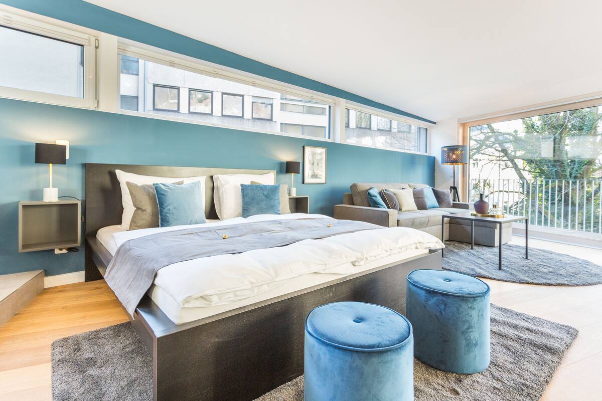 Quarto moderno com uma cama grande, um sofá e uma pequena mesa.