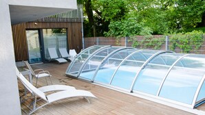 A covered swimming pool with lounge chairs and a wooden deck. - Room 4 & 5 Apartments (Salzburg)
