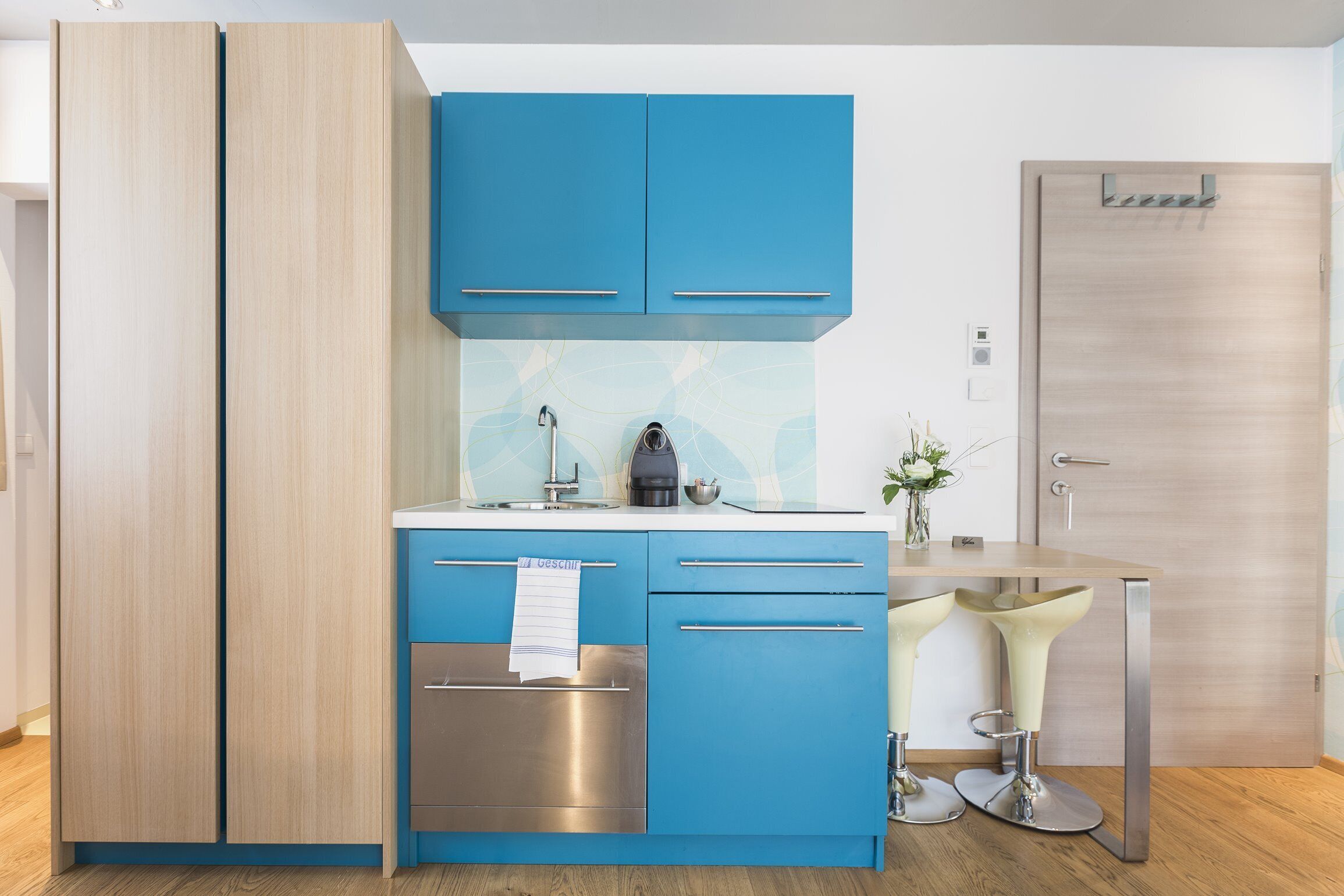 Une cuisine moderne avec des meubles bleus, un four en acier inoxydable et une machine à café.