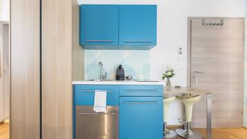 Une cuisine moderne avec des meubles bleus, un four en acier inoxydable et une machine à café.