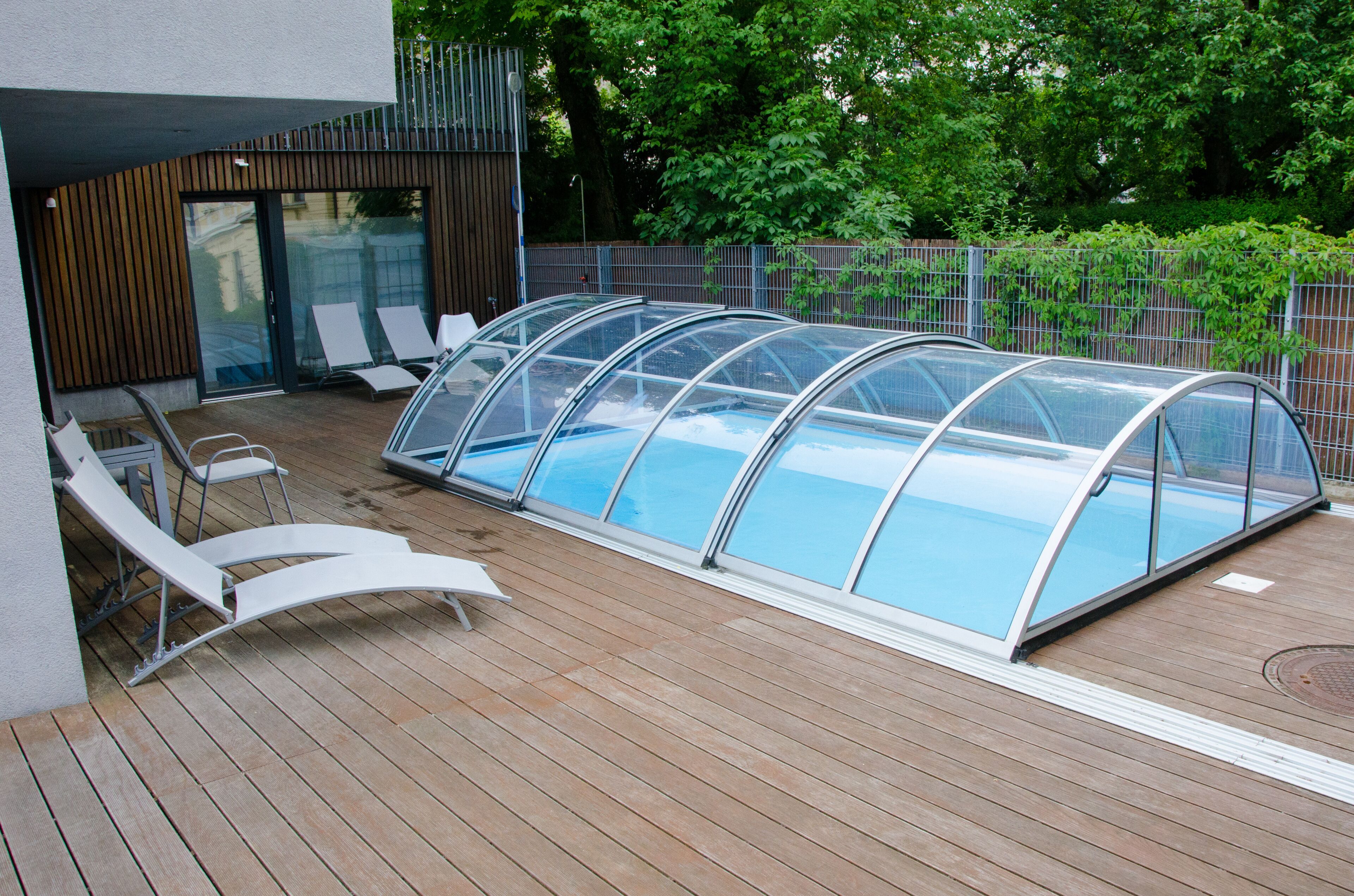 Una piscina techada con sillas de descanso y una terraza de madera.